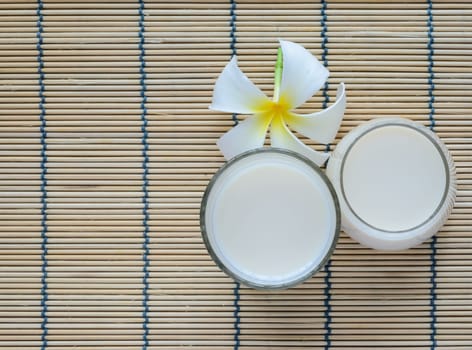 Fresh Soy milk (Soya milk) on bamboo place mat with white plumeria flower. Traditional staple of East Asian cuisine