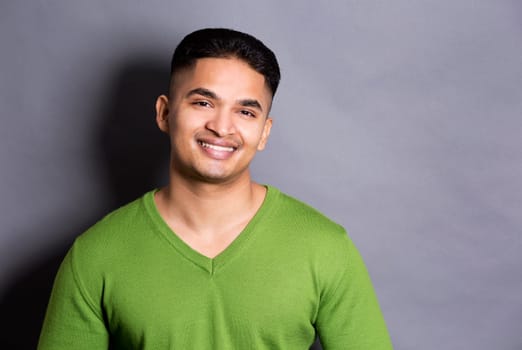 young casual man wearing green on grey background