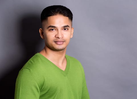 young casual man wearing green on grey background