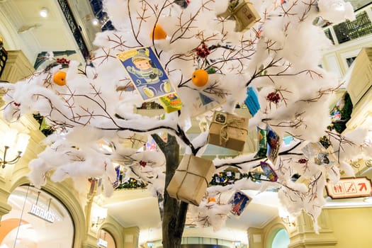 Moscow, Russia - January 05, 2016: Christmas toys and gifts hanging on an artificial tree covered with snow cotton wool