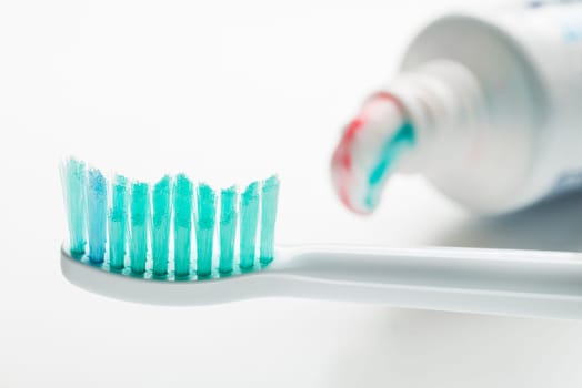 Toothbrush and toothpaste on white background close up.