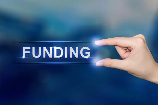 hand pushing funding button on blurred blue background