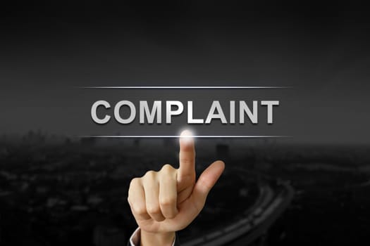 business hand clicking complaint button on black blurred background