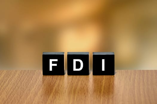 FDI or Foreign direct investment on black block with blurred background