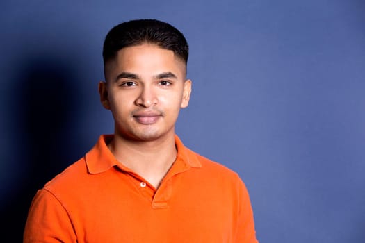 young casual man wearing orange tshirt on blue background