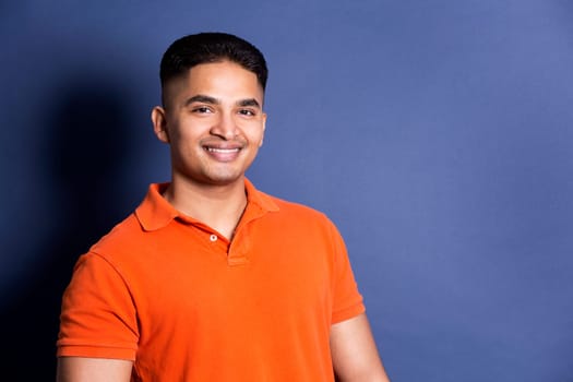 young casual man wearing orange tshirt on blue background