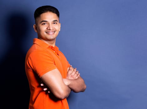 young casual man wearing orange tshirt on blue background