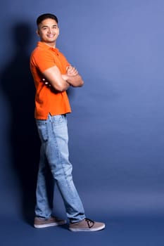 young casual man wearing orange tshirt on blue background