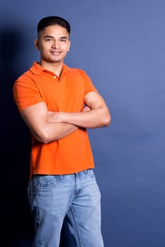 young casual man wearing orange tshirt on blue background