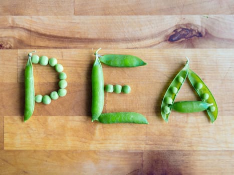 Word PEA created with peas on a wooden board