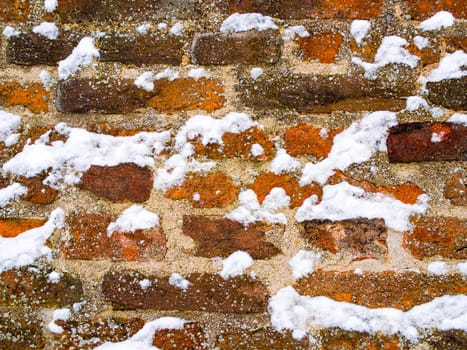 Detail of red brick and concrete wall lightly covered with snow flakes, winter time illustration, background, pattern