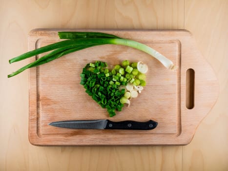 Heart shaped pile of bunching onion on the wooden board, from the top view, healthy life style