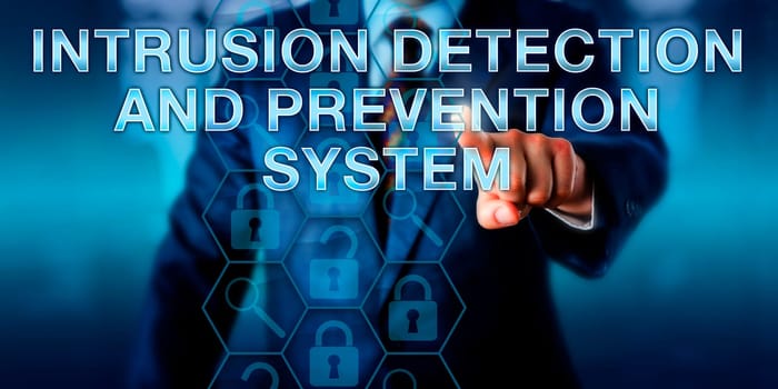 Computer security specialist is pushing INTRUSION DETECTION AND PREVENTION SYSTEM on a touch screen interface. Business metaphor and information technology concept. Copy space over office background.