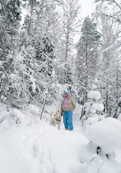 The woman with a dog on walk in a winter wood