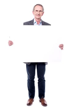 Senior man standing behind placard over white
