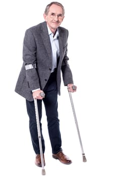 Smiling senior man walking with two crutches