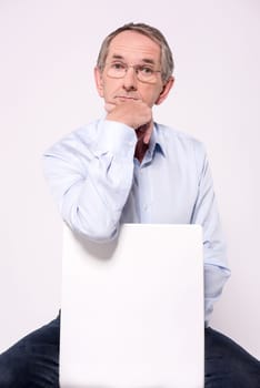 Pensive senior man sitting behind ad board