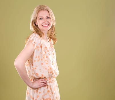 blond woman wearing beige dress on green background