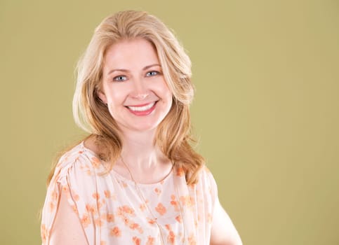 blond woman wearing beige dress on green background