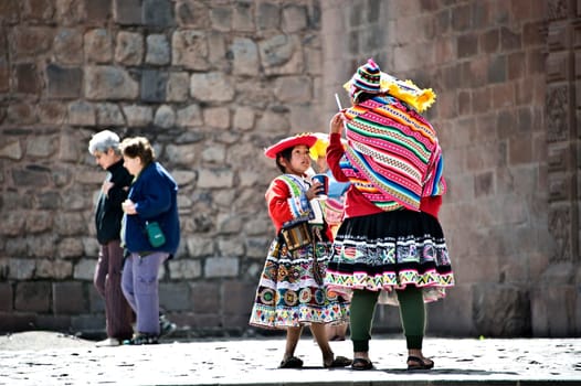 CUZCO, PERU, AUGUST 1 - Quechua Indians break from posing with tourists, drinking sodas - August 1, 2011 in Cuzco, Peru