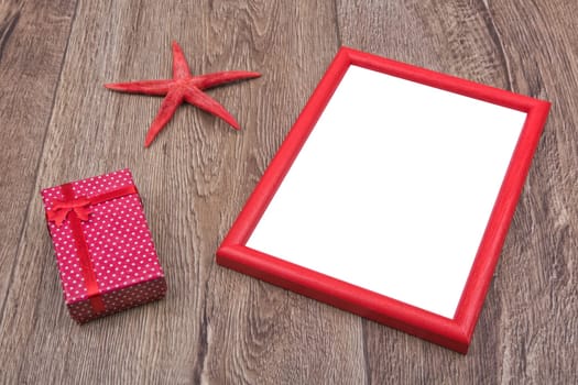 Red starfish, gift and photo frame on a brown wooden background