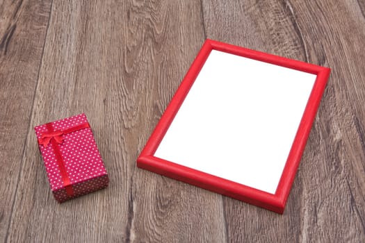 Gift and photo frame on a brown wooden background