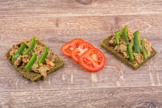 Raw bread with a spread decorated with green pepper and tomatoes