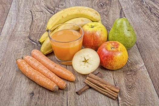 Blended fruit smoothie with ingredients on wooden table