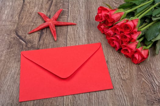 Envelope, red starfish and roses on a wooden background