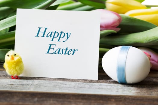 Happy Easter greeting card surrounded by Easter egg, flowers and watchful chick.