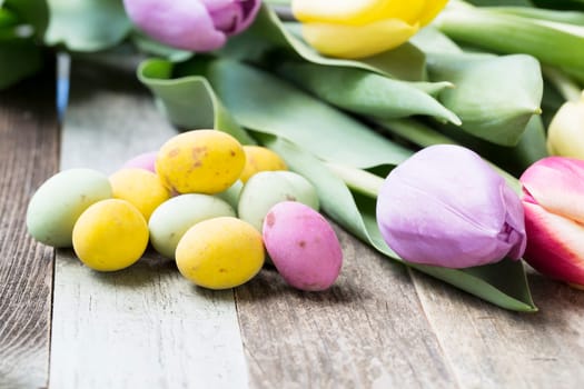 Close up of milk chocolate eggs on table with flowers.
