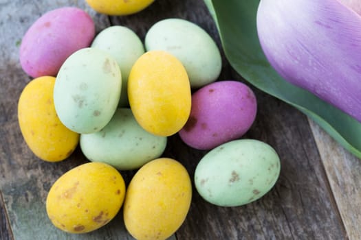 Close up of milk chocolate eggs on table with flowers.