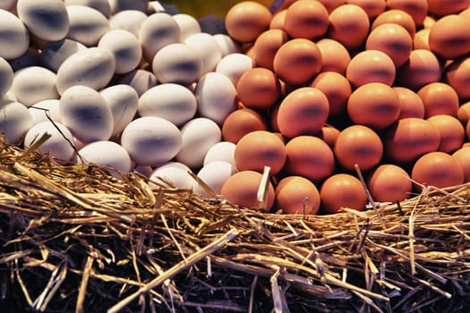 White and browns eggs over straw in a shop, La Boqueria market, Spain, Barcelona. Vintage filtered