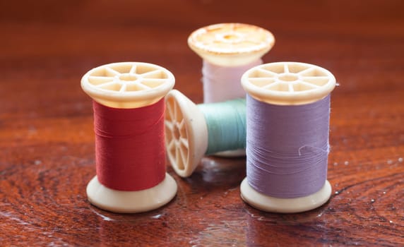 Vintage grunge colorful thread spool on wooden table, stock photo