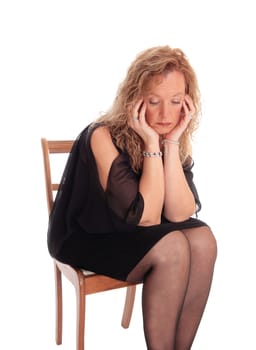 A blond woman sitting on a chair with her face in her hand looking very.sad, isolated for white background..