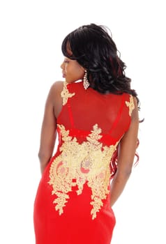A gorgeous African American woman standing in a long red evening dress.with gold embroideries and long black hair isolated for white background..