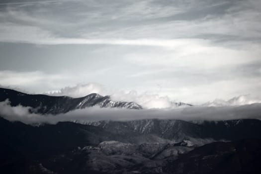 Clouds and fog move over the peaks and ridges of a mountain range.