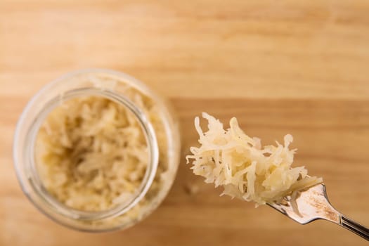 Sauerkraut on a fork with jar below and copy space.