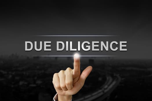 business hand clicking due diligence button on black blurred background