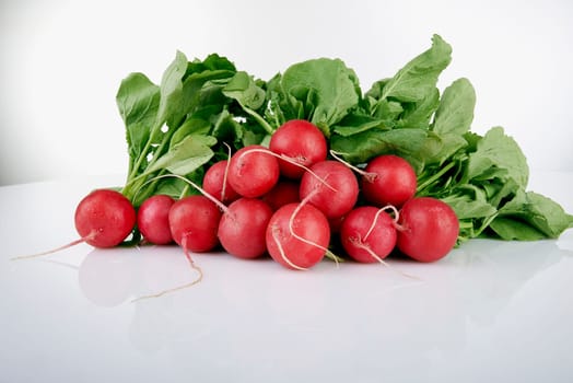 Bunch of fresh radishes on white with soft shadow.