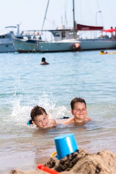 young boys lying in the sea and splashing water