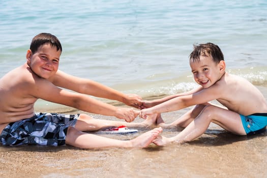 Two young boys sitting by the sea