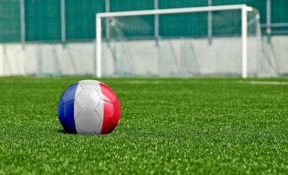 Soccer ball with the flag from France on the green field
