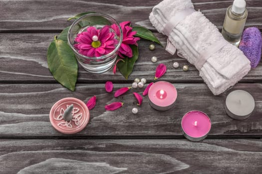 Spa concept. Lavender oil, flowers,cadles and bath white towels on wooden background.