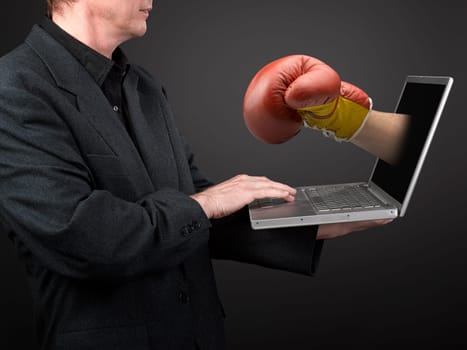 Man in black shirt and suit holding a laptop and win Boxing glove punch