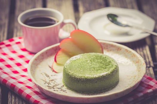 Green tea cake in palte with black coffee on wooden