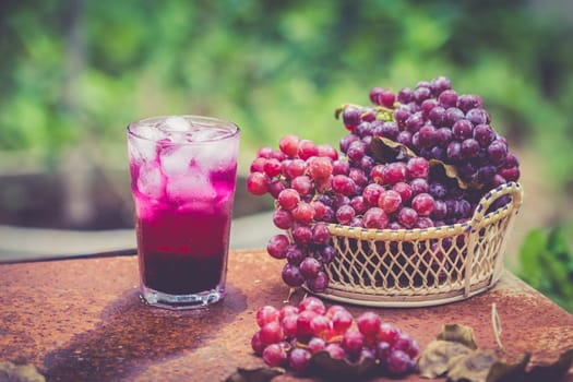 Red grape fruits and grape juice on wooden