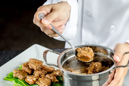 Chef making stir fried chinese kale and pork ribs in the kitchen