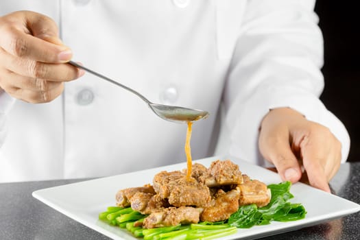 Chef making stir fried chinese kale and pork ribs in the kitchen