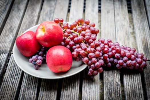 Red grape fruits with apple in the dish on wooden